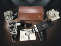 A collection of vintage 8mm home movie cameras including a Bolex Paillard with grip attachment and