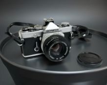 An Olympus OM-1 35mm film camera with Zuiko MC Auto-S 1:1.8 f=50mm lens.