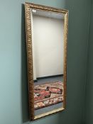 A contemporary mirror in ornate frame, 56 cm x 141 cm.