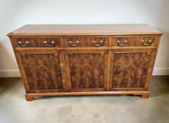A reproduction yew wood triple door sideboard, 150 cm x 41 cm x 84 cm.