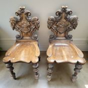 A pair of 19th century continental heavily carved oak hall chairs, width 47 cm.
