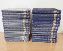 A collection of New Book of Knowledge volumes, published by Grolier, mostly sealed in cellophane.