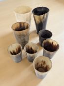 A group of polished horn beakers and a wooden carving of an elephant and a monkey.