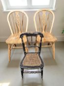 A pair of pine wheel back chairs and a further ebonised child's chair.