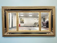 An impressive contemporary ebonised and gilt triple section bevelled mirror, 230 cm x 132 cm.