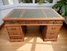 A reproduction yew wood nine drawer twin pedestal desk with leather inset top,