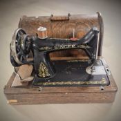 An antique Singer hand sewing machine in oak case