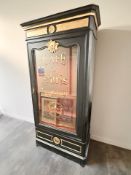 A gilt and ebonised glazed single door display cabinet with decoration 'Cafe De Paris',
