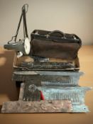An angle poised lamp, an antique doctor's Gladstone bag, metal plaques.