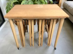 A teak nest of five tables on castors, width 62 cm.