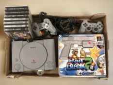 A Sony Playstation 1 console, controllers, a Namco gaming pistol in box and several games.