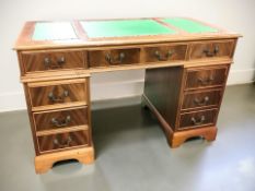 A reproduction yew wood nine drawer twin pedestal desk with brass studded green leather inset