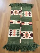 A 20th century woolen rug on green ground, 140 cm x 63 cm.