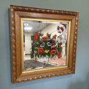 An Edwardian bevelled mirror with painted decoration depicting a bowl of flowers in an oak frame,