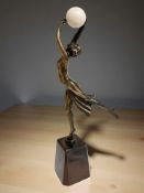 A patinated metal and celluloid figure of an Art Deco dancer holding a ball aloft, height 35cm.