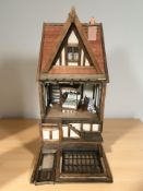 An Elizabethan style doll's house containing some furnishings including a four poster bed,