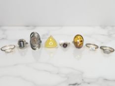 Eight silver/white metal dress rings, set with topaz, amber,