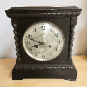 A late Victorian carved and ebonised oak eight day mantel clock, with silvered dial,