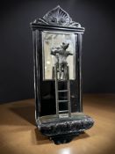 A 19th century carved and ebonised wall mirror surmounted by a figure standing on a ladder,
