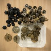 A collection of military cap badges, army and navy buttons, etc.