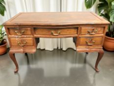 A reproduction hardwood five drawer writing desk on cabriole legs, 127 cm x 59 cm x 77 cm.