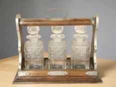 A Victorian oak and silver plate three bottle tantalus, width 39 cm.