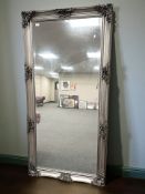 A reproduction bevelled overmantel mirror in a silvered frame, 90 cm x 180 cm.