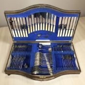 An oak serpentine canteen containing a part-service of EPNS and stainless steel cutlery.