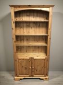 A modern pine open bookcase fitted cupboards beneath, 100 cm x 32 cm x 188 cm.