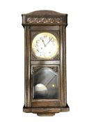 An early 20th century oak eight day wall clock with silvered dial, with pendulum and key,