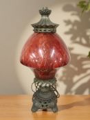 An ornate metal table lamp with red glass shade,