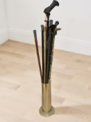 A brass stick pot containing assorted walking sticks and canes including two with silver pommels.