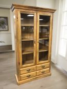A contemporary glazed double door bookcase, fitted four drawers beneath, 101 cm x 36 cm x 175 cm.