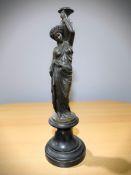 A patinated bronze statue of a Greek lady holding an urn aloft on black socle plinth,