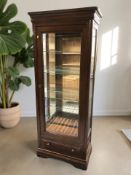 An Ernest Menard mahogany effect glazed single door display cabinet with glass shelved interior and