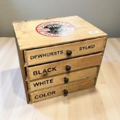 A four-drawer counter top pine chest, with later Dewhurst's advertising, width 32 cm.