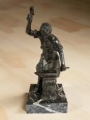 A patinated metal figure of a blacksmith on square marble plinth, height 32 cm.
