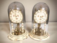 A pair of Kundo anniversary clocks under shades,