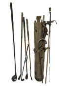 A canvas golf bag containing vintage clubs, walking stick with silver pommel, fencing foil,