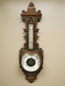 A heavily carved oak aneroid barometer marked 'Sutton of Whitehaven', height 87 cm.