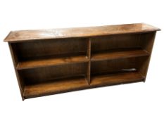A reproduction stained elm low open bookcase, 138 cm W x 27 cm D x 64 cm H.