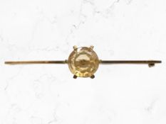 A gold bar brooch set with a large citrine, stamped 15ct, width 6.5cm.