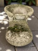 A weathered concrete garden planter in the form of a boot,