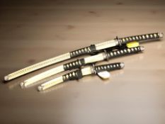 A trio of reproduction Japanese graduated swords in scabbards.