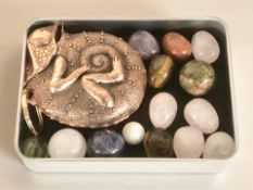 A small tin of various semi precious polished stones and a tape measure in the form of a chameleon.