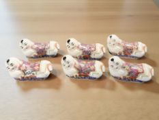 A set of six oriental ceramic chopstick rests in the form of recumbent babies, length 7 cm.