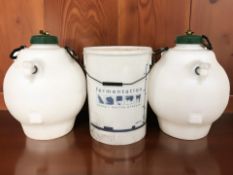 A plastic fermentation bucket and a further pair of plastic vessels with taps.