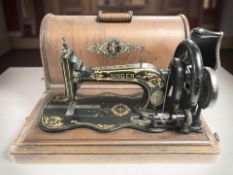 An antique Singer hand sewing machine in walnut case.