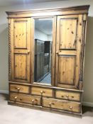 A reproduction pine mirrored triple door wardrobe, fitted five drawers beneath,