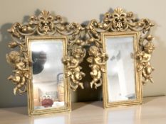 A pair of reproduction gilt plaster rectangular wall mirrors, flanked by cherubs,